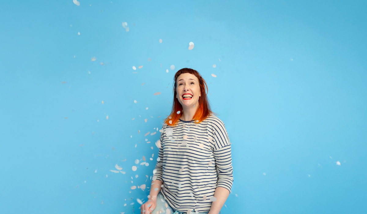 48 Thoughts Per Minute shows a single lady looking happy with white confetti in the air. The image promotes The Paper Birds new show - 48 Thoughts Per Minute
